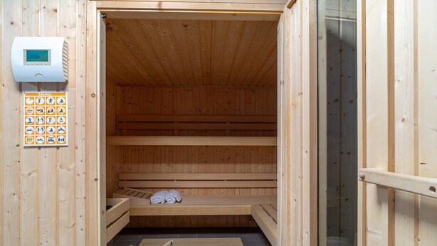 Un sauna avec des bancs en bois, un panneau de commande et un plancher en bois.