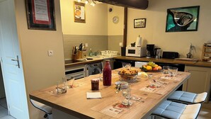 Cozinha com ilha de madeira, micro-ondas, cafeteira e uma fruteira.