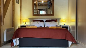 Quarto com uma cama grande, duas mesas de cabeceira com abajures, uma escada de madeira e um espelho na parede.