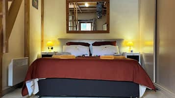 Une chambre à coucher avec un grand lit, deux tables de chevet avec des lampes, une échelle en bois et un miroir au mur.