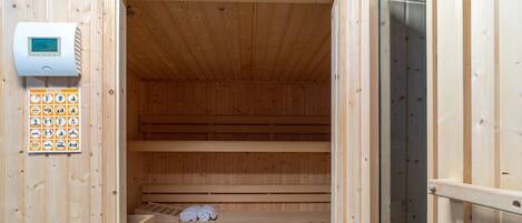 Eine Sauna mit Holzbänken, einer Steuerung und einem Holzboden.