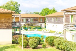 Un espace piscine comprenant des chaises longues, une pergola et un petit jardin.