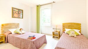 Ein Zimmer mit zwei Betten, einem Nachttisch, einem Fenster mit Vorhängen und einem an der Wand hängenden Bild.