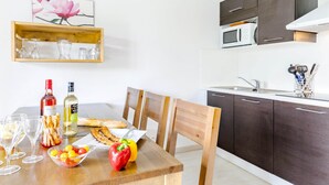 Eine moderne Küche mit dunklen Schränken, einer Mikrowelle und einem Essbereich mit einem Holztisch, gedeckt für eine Mahlzeit.