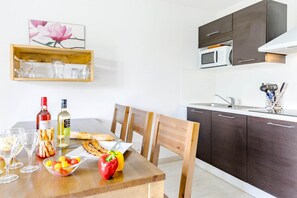 Eine moderne Küche mit dunklen Schränken, einer Mikrowelle und einem Essbereich mit einem Holztisch, gedeckt für eine Mahlzeit.
