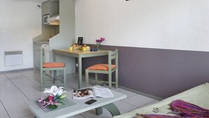 Un espacio habitable compacto con kitchenette, comedor y sofá.