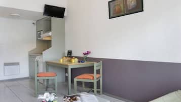 Un espace de vie compact comprenant une kitchenette, un coin repas et un canapé.