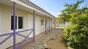 Eine Reihe weißer Gebäude mit violetten Kreuzstreben, ein Kiesweg und ein grüner Busch.