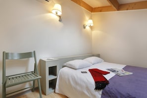 Ein Schlafzimmer mit einem Bett, einem Nachttisch, einem Sessel und zwei Wandlampen.
