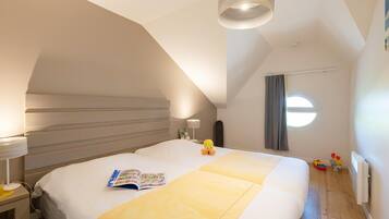 Une chambre à coucher avec un grand lit, une table de chevet avec une lampe, une fenêtre avec des rideaux et un luminaire au plafond.