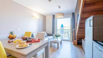 Une chambre d’hôtel moderne dotée d’un coin repas, d’un canapé, d’une table basse et offrant une vue sur l’extérieur.