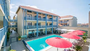 Un hôtel doté d’une piscine, de balcons et d’un espace extérieur aménagé avec des parasols.