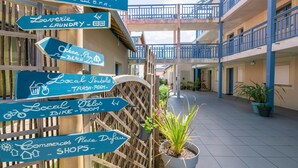 Ein Innenhof mit Hinweisschildern zu Einrichtungen wie Schwimmbad, Wascherei, Strand, Müllraum, Fahrradraum und Geschäften.