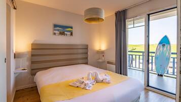 Habitación de hotel con cama, un cuadro, una lámpara, una ventana con vistas y una tabla de surf.