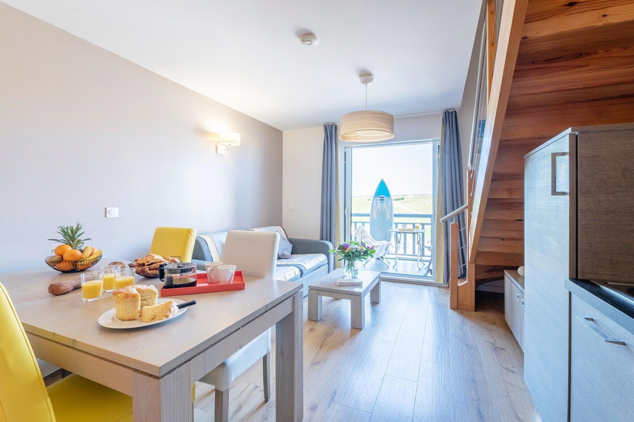Ein modernes Hotelzimmer mit Essbereich, einer Couch, einem Couchtisch und Blick ins Freie.