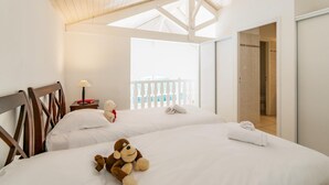 Ein Hotelzimmer mit zwei Betten, einer Holzbalkendecke, einem Balkon mit weißer Brüstung und einer Duschkabine.