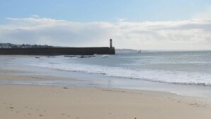 Une plage avec un phare et une digue rocheuse.