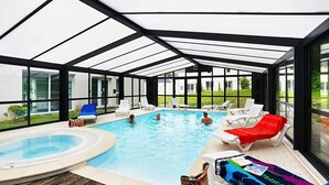Ein Pool mit Glasumrandung, Liegestühlen und einem Whirlpool.