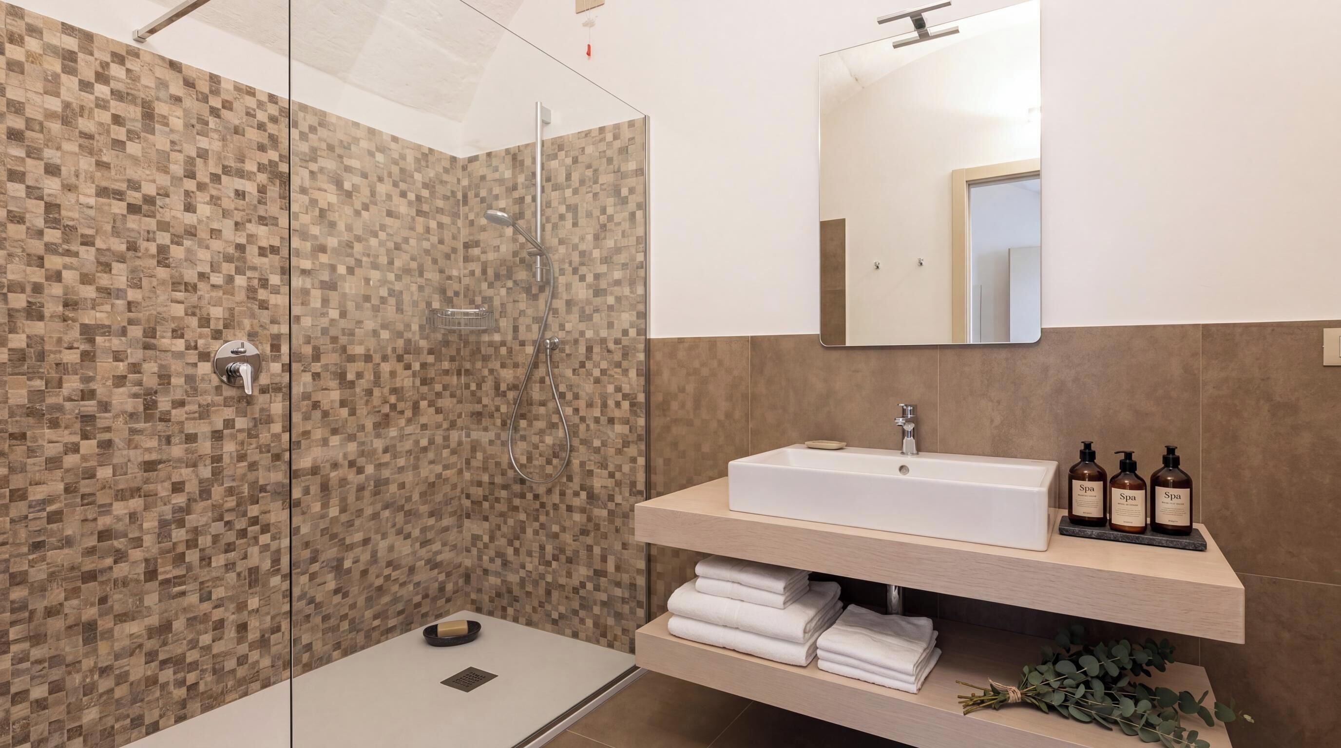 A modern bathroom with a shower, a sink, and a mirror.