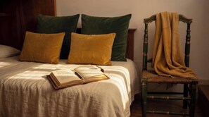 A bed with a book, pillows, and a chair with a blanket. - Edward Historic House (Gubbio)
