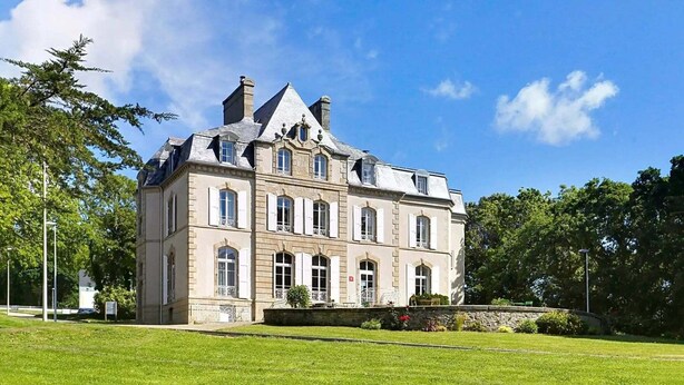A large, historic building with multiple windows and a symmetrical facade, surrounded by a well-maintained lawn. - Spacious Coastal Duplex Cottage for 8 (Audierne)
