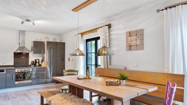 A modern kitchen with stainless steel appliances, a wooden dining table, and a bench. - Chalet Near Skilift & Bikepark in Leogang (Leogang)