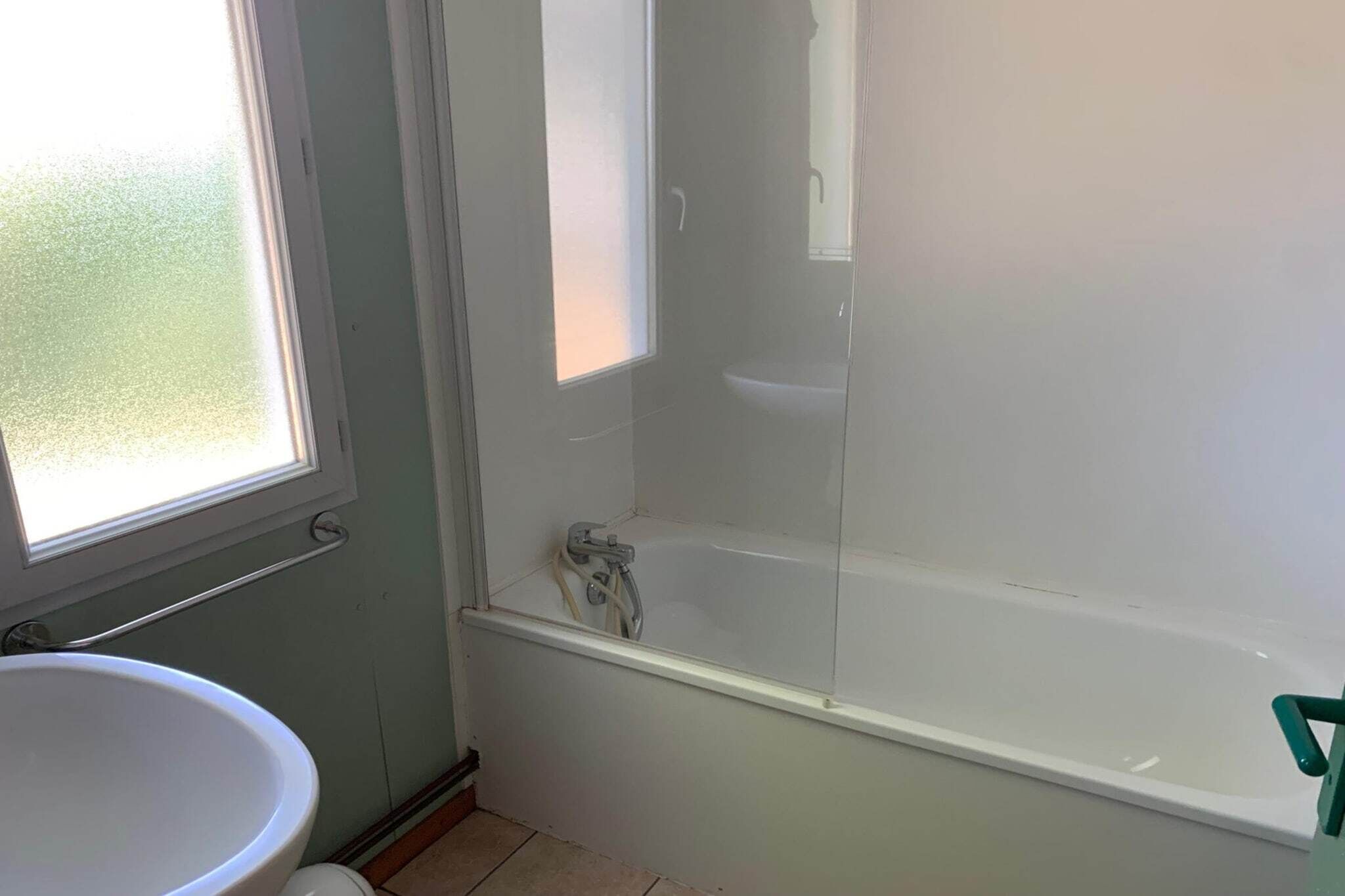Ein Badezimmer mit einer Badewanne, einem Fenster und einem Waschbecken.