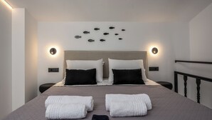 Ein Hotelzimmer mit einem Bett, zwei Nachttischen, einem Kopfteil, Wandleuchten und einer Fischdekoration an der Wand.