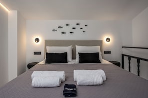 Ein Hotelzimmer mit einem Bett, zwei Nachttischen, einem Kopfteil, Wandleuchten und einer Fischdekoration an der Wand.