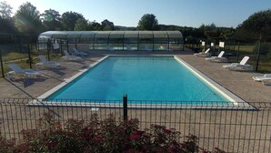 En pool med solstolar och ett överbyggt område.