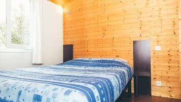 Una stanza con rivestimenti in legno, un letto, una finestra e due altoparlanti.