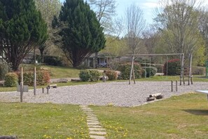 Ein Spielplatz mit Kiesweg, Bäumen und einer Rasenfläche.