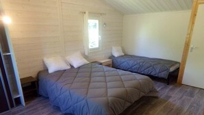 Ein Zimmer mit zwei Betten, einem Fenster und einer Tür.