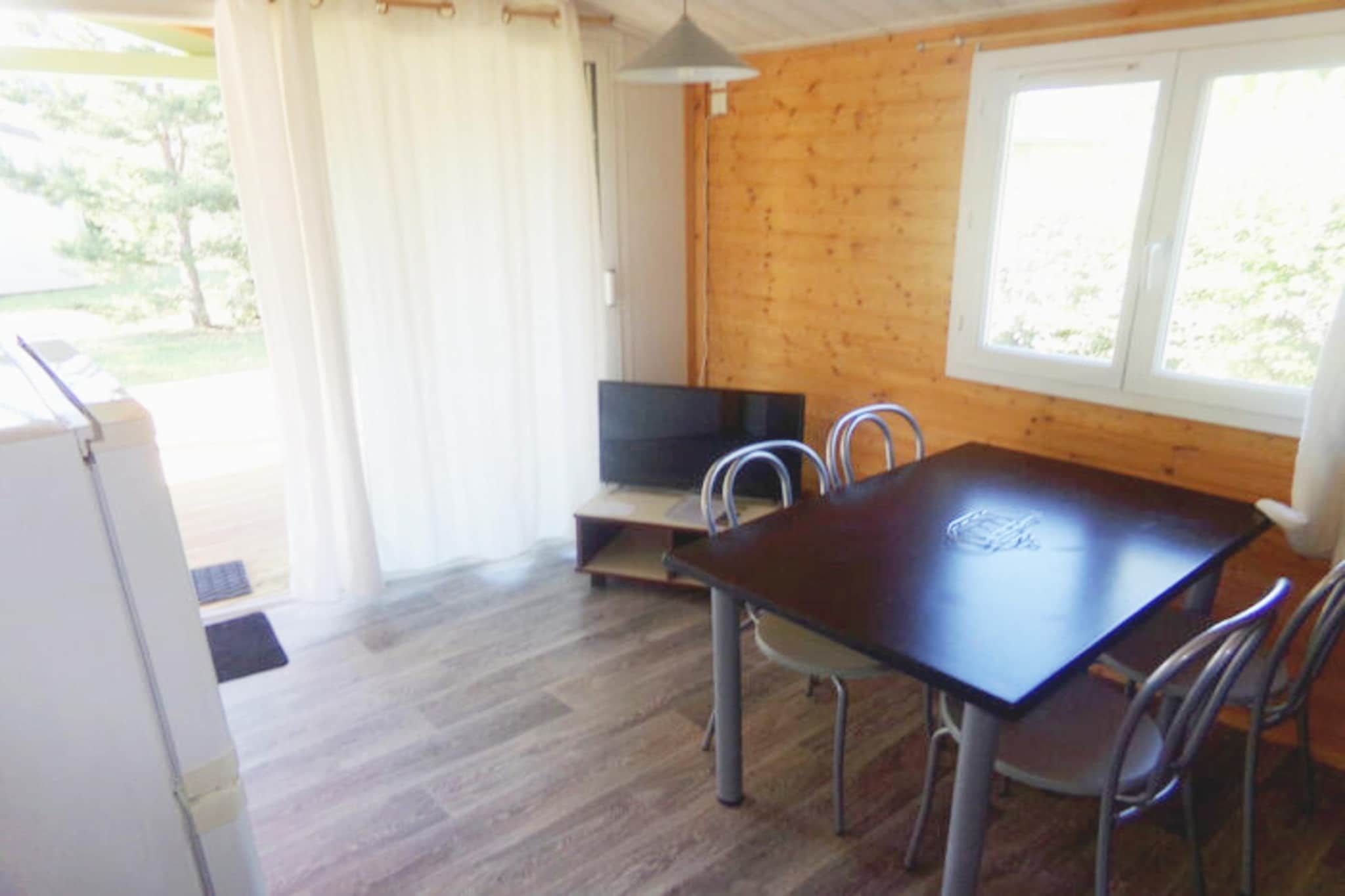 A wooden cabin with a dining table, chairs, a television, and a window.