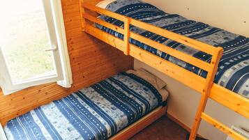 A bunk bed with a window, a lower bunk with a patterned mattress, and a headboard.