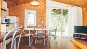 Een houten interieur met een eettafel, stoelen, een televisie en een schuifdeur naar een buitenruimte.