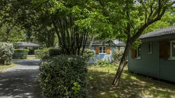 Una hilera de cabañas pequeñas y verdes, con un camino pavimentado que las conduce, rodeadas de vegetación densa.