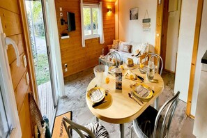 Ein Holzblockbau-Innenraum mit Esstisch für zwei Personen, einer Couch und einem Fernseher.