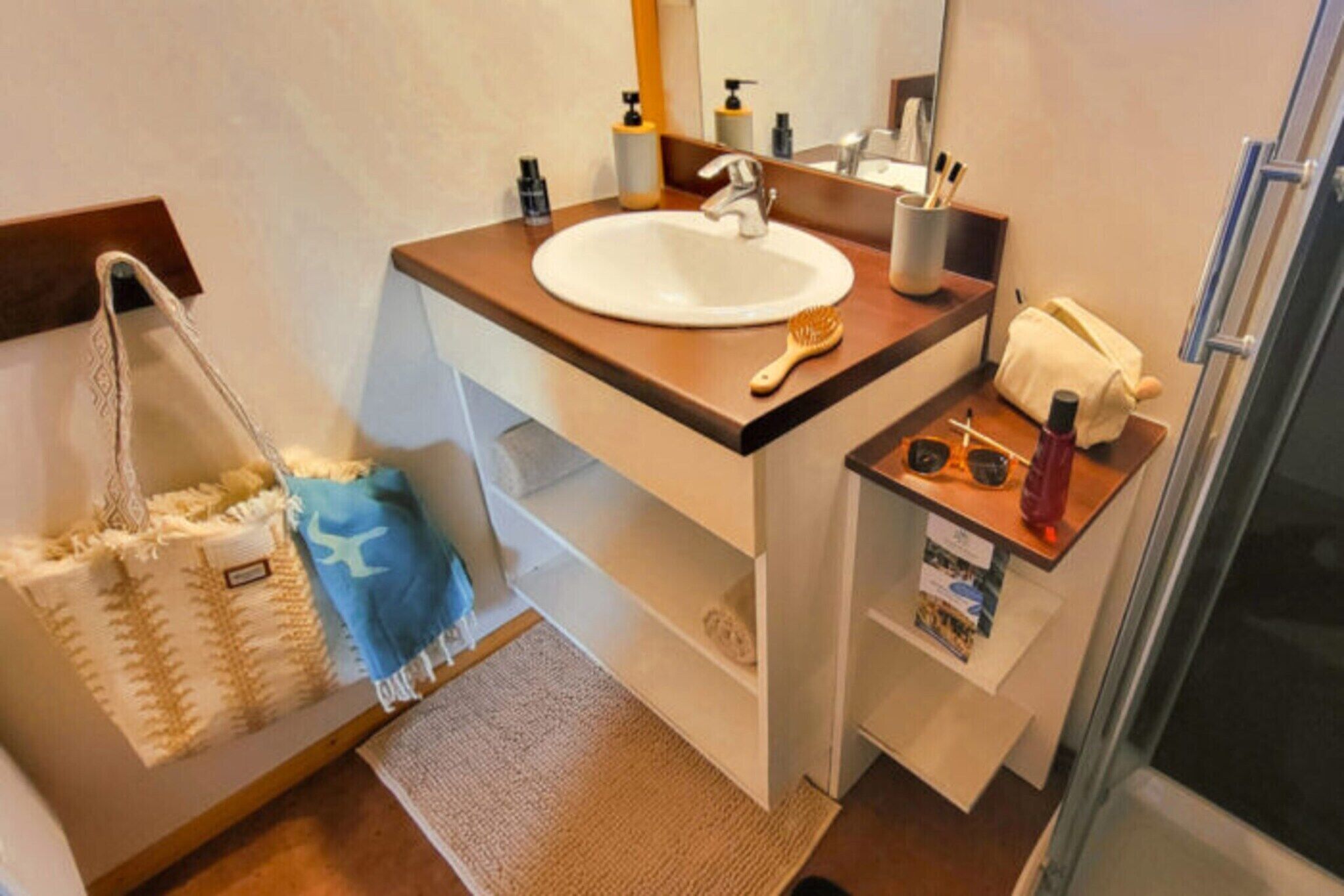 A bathroom with a sink, mirror, towel rack, and a small shelf with toiletries.