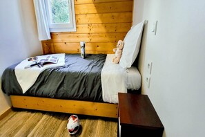 Ein Einzelbett mit Holz-Kopfteil, ein Nachttisch, ein Fenster mit Vorhängen und ein Fußball auf dem Boden.