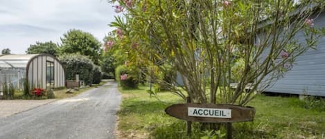 Un camino rural que conduce a una propiedad, con un letrero que dice 'ACCUEL'.