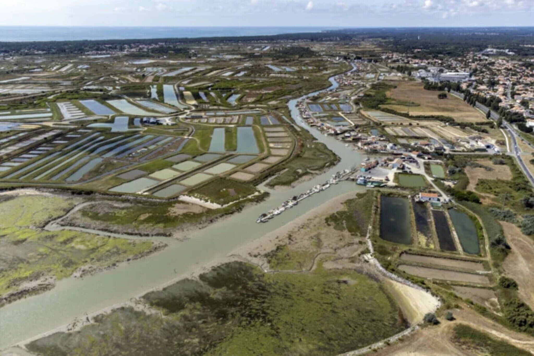 An aerial view of a coastal area with multiple water channels, a river, and a town with buildings.