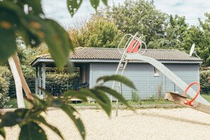 Ein kleines Haus mit geneigtem Dach, einer Leiter und einer Schaukel.