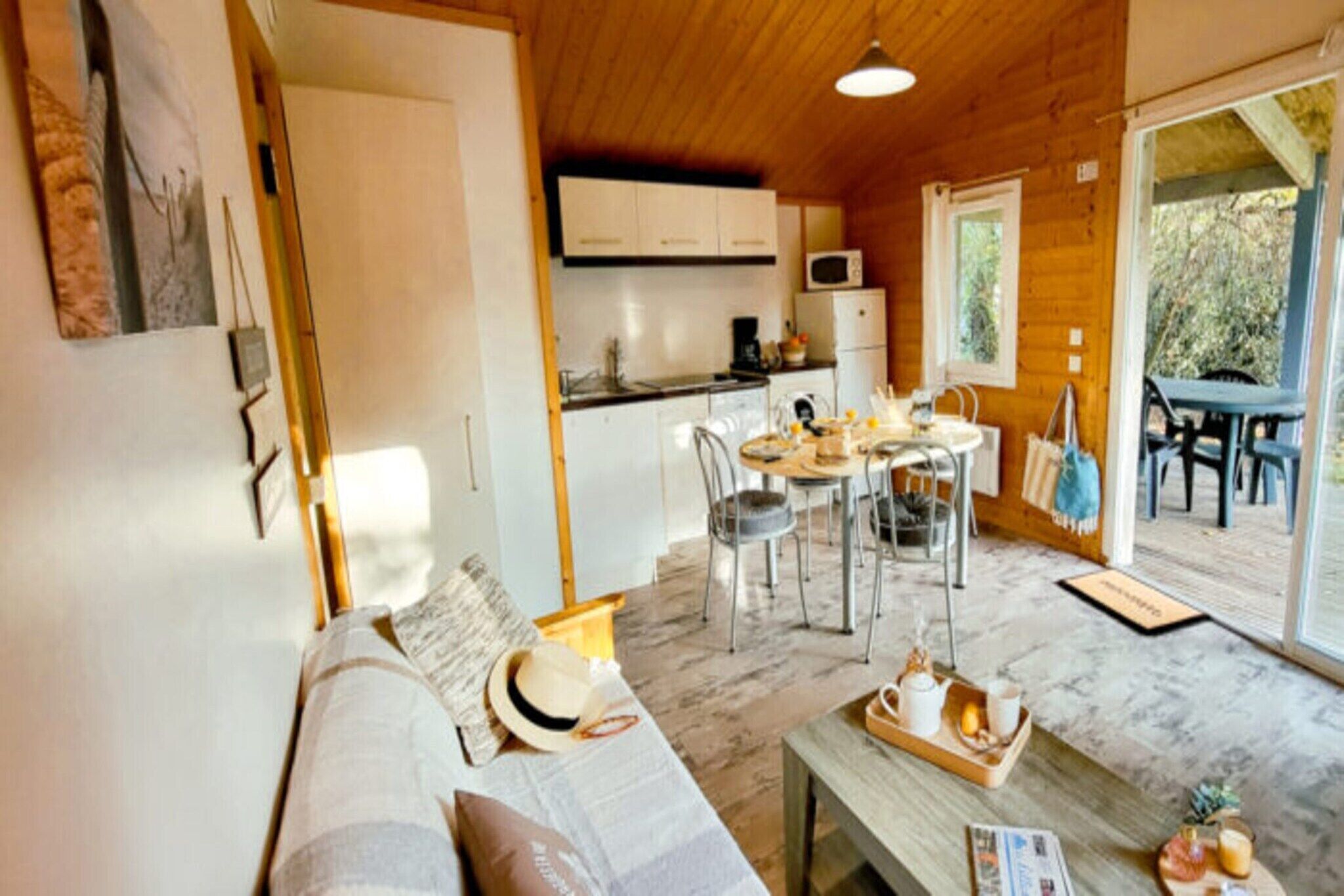 Ein gemütliches Interieur mit einer Couch, einem Esstisch, Stühlen und einer Küchenzeile mit Schränken und Geräten.