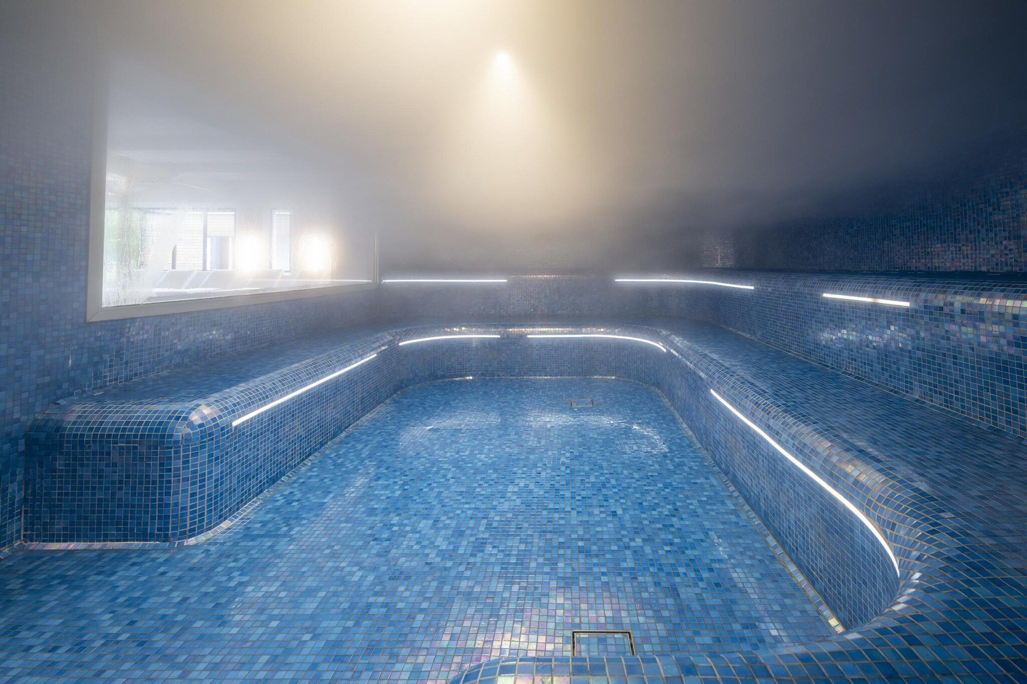 A large indoor swimming pool with tiled walls and a curved design.