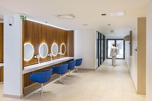 A modern reception area with a wooden panel wall, a reception desk, and blue chairs. - Spa Retreat in La Roche-Posay (La Roche-Posay)