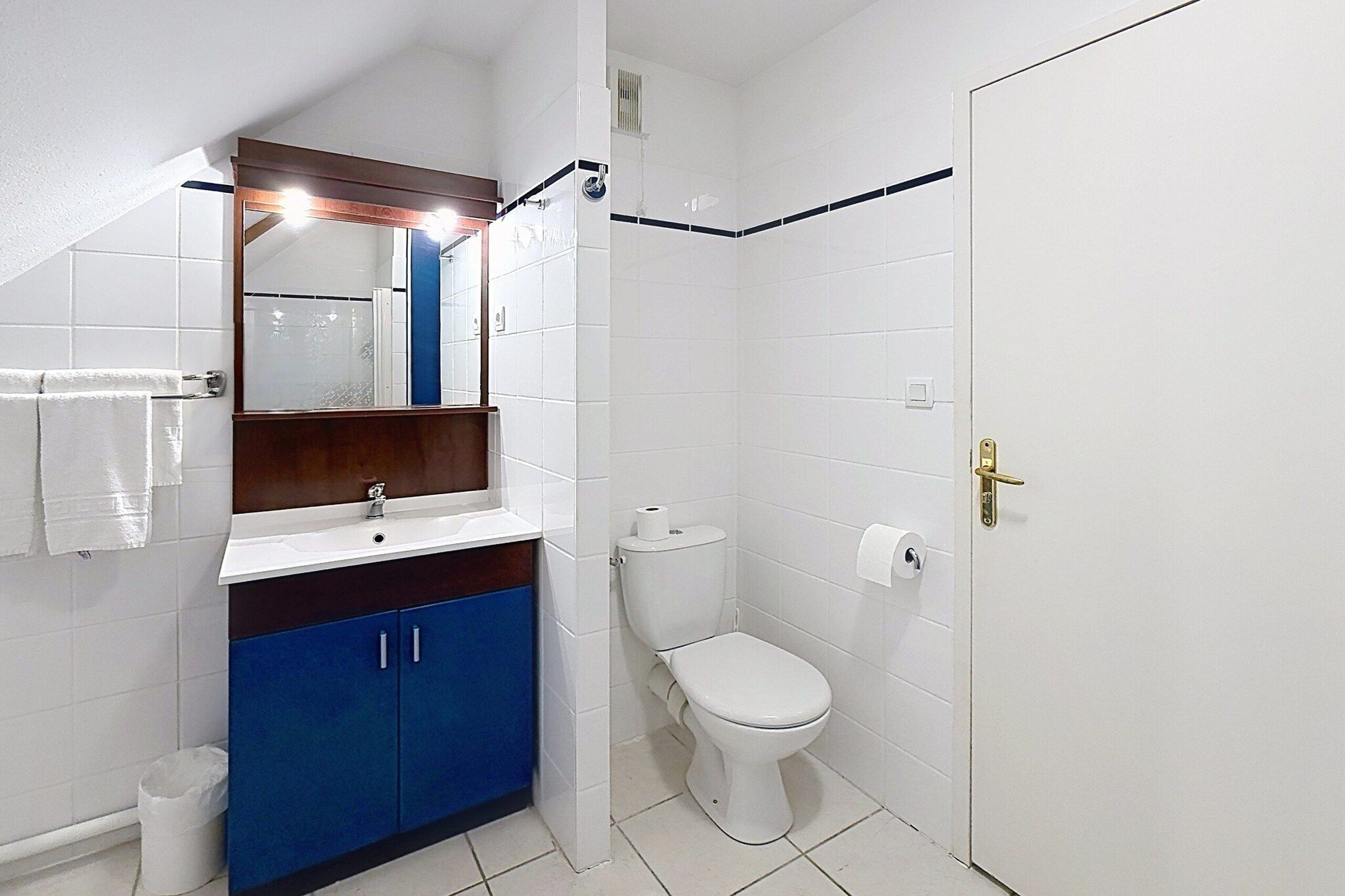 Un bagno con un WC bianco, un lavabo con uno specchio sopra e mobili azzurri.