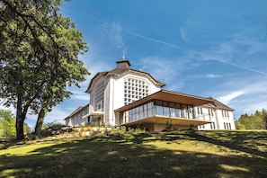 Un grand bâtiment blanc, doté d’une tour centrale imposante, de grandes fenêtres et d’un toit en pente.