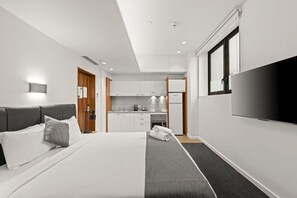 A modern hotel room with a bed, a TV, a kitchenette, and a bathroom. - Comfort Inn Geelong (Geelong)