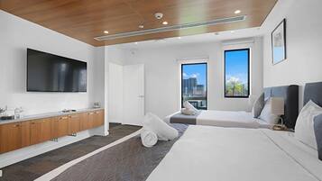 Een moderne hotelkamer met een groot bed, een flatscreen televisie, een houten plafond en uitzicht over de stad.